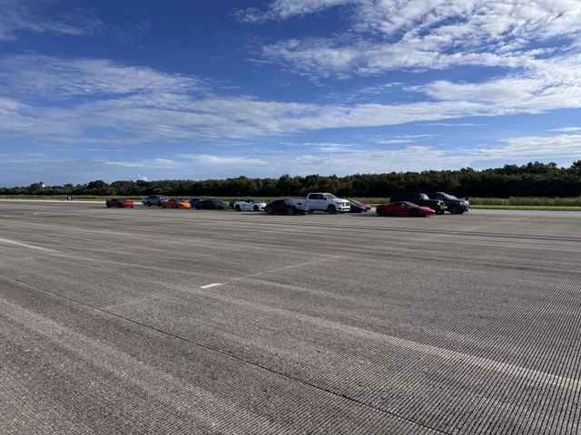 Sports cars and performance vehicles lined up along the runway.