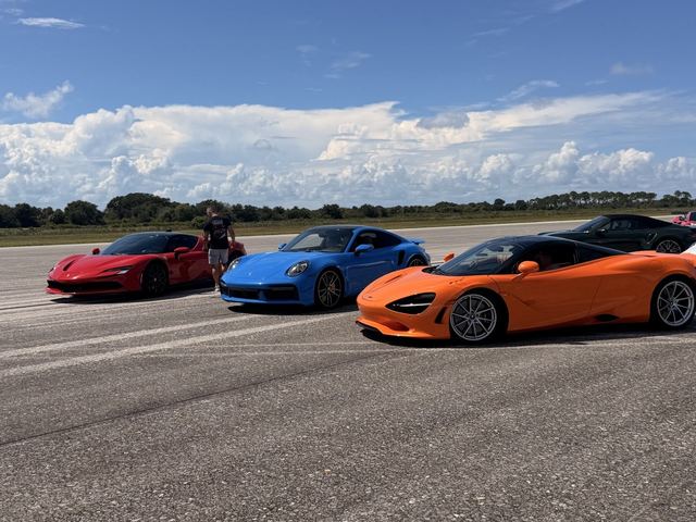 Three supercars in red, blue and orange parked side by side on the runway.