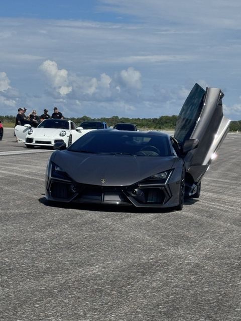A dark supercar with its gullwing doors raised at the event.