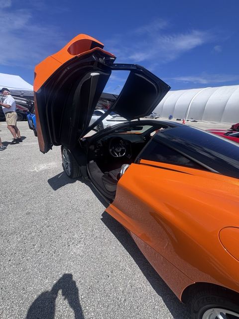 An orange sports car with its dihedral doors open.