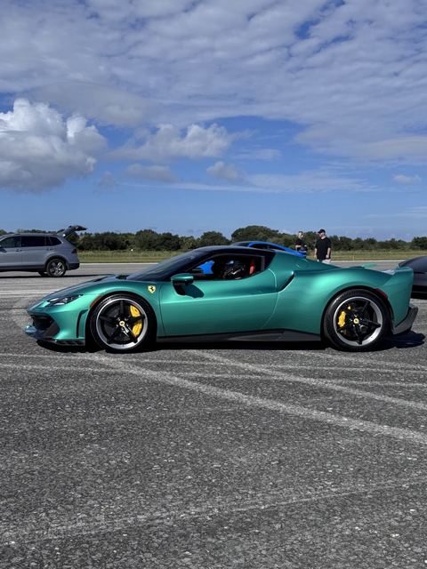 A teal sports car with yellow brake calipers on the track.