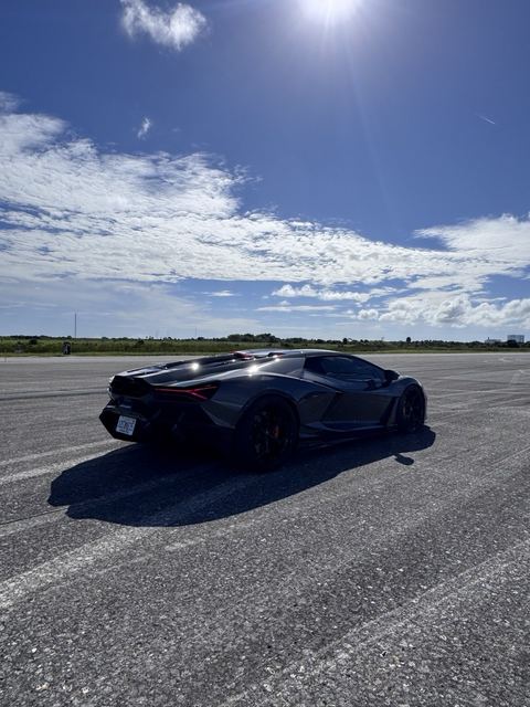 A black sports car parked on the open runway.