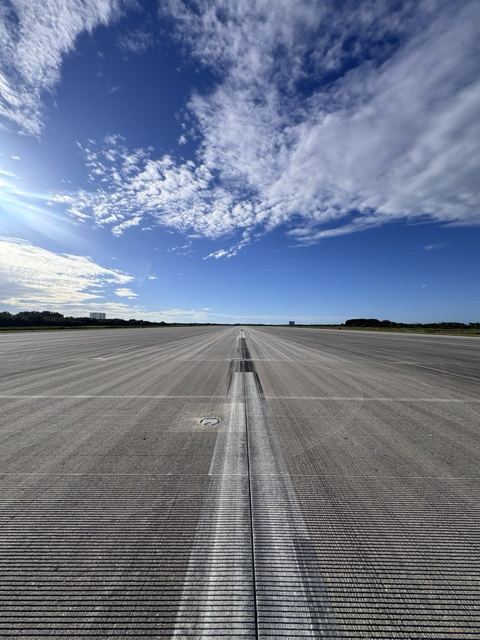 The concrete runway running out to the horizon under a blue sky.