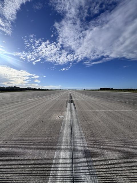 The empty paved runway with painted markings stretching to the horizon.