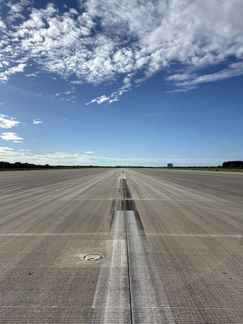 An empty stretch of concrete runway with tyre marks.